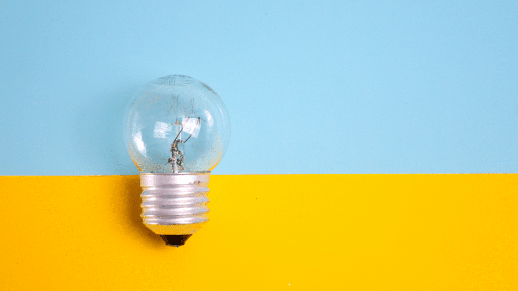 A light bulb placed in front of a blue and yellow background.